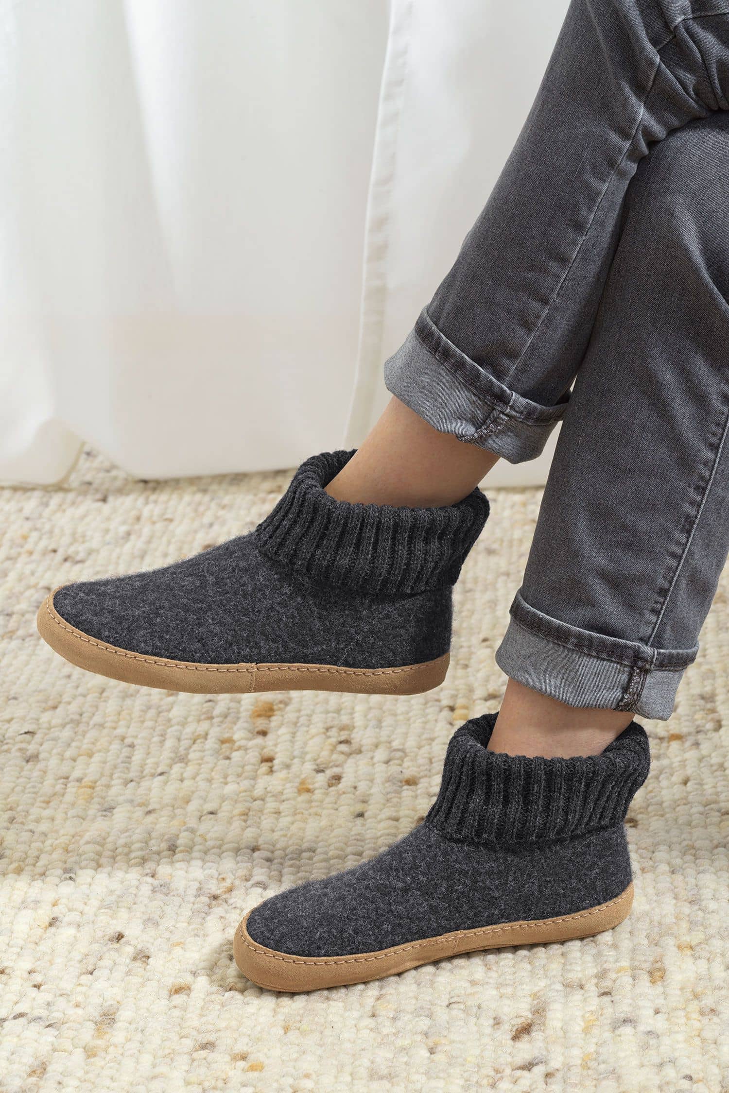 Person trägt graue Finkhof Hüttenschuhe aus bio Wolle (kbT), Sohle aus pflanzlich gegerbtem Rindsleder, seitlich zu sehen