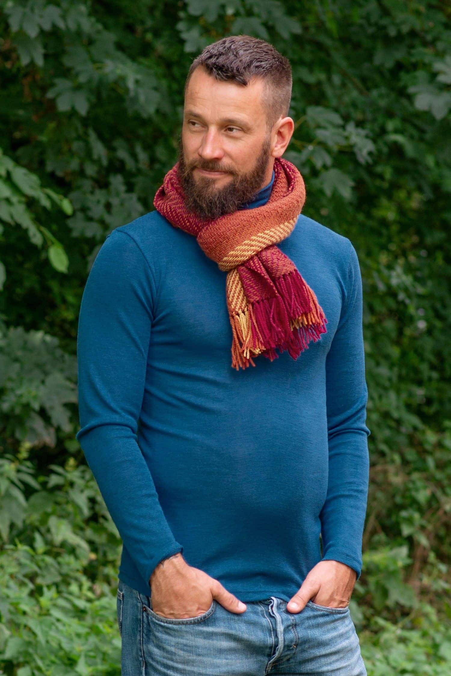 Mann mit blauem Pulli trägt pflanzengefärbten und handgewebten Wollschal in orange aus bio Wolle (kbT) vom Finkhof