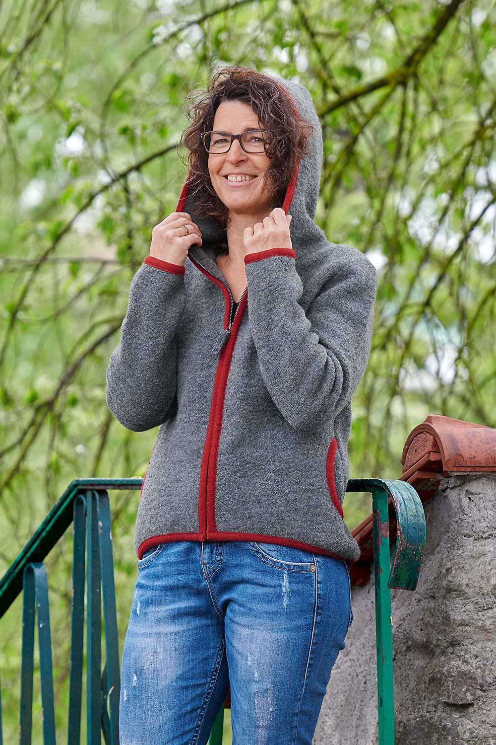 Frau setzt sich Kapuze von grauer Strickwalk Jacke aus bio Wolle (kbT) vom Finkhof auf