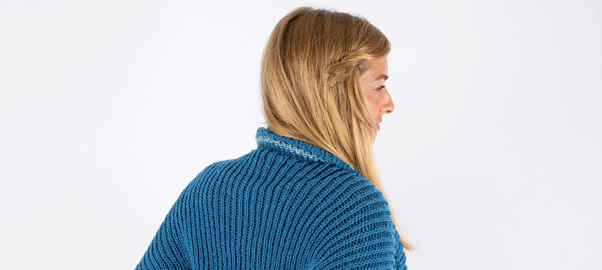 Strickanleitung Seelenwärmer in Halbpatent Frau mit blonden Haaren hat sich blauen Strickseelenwärmer um Schultern gelegt