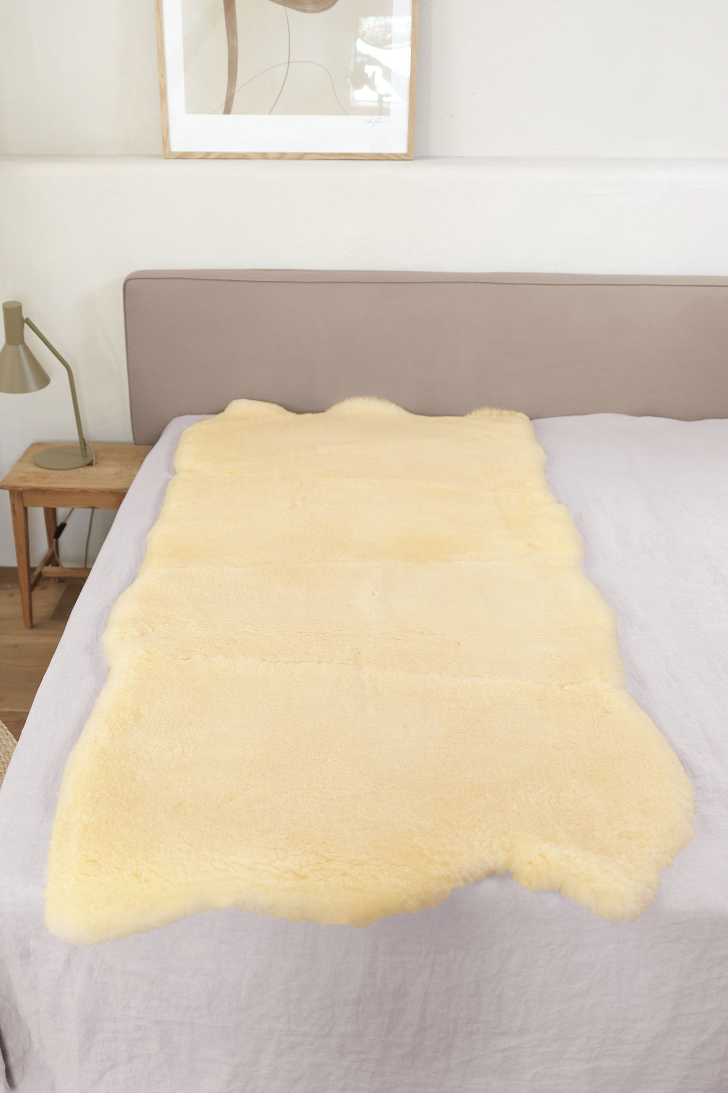 Felldecke natürliche Fellform relugan gegerbt 90 x 200 cm relugan gegerbte Felldecke in natürlicher Form aus Schaffell vom Finkhof auf grauem Bett
