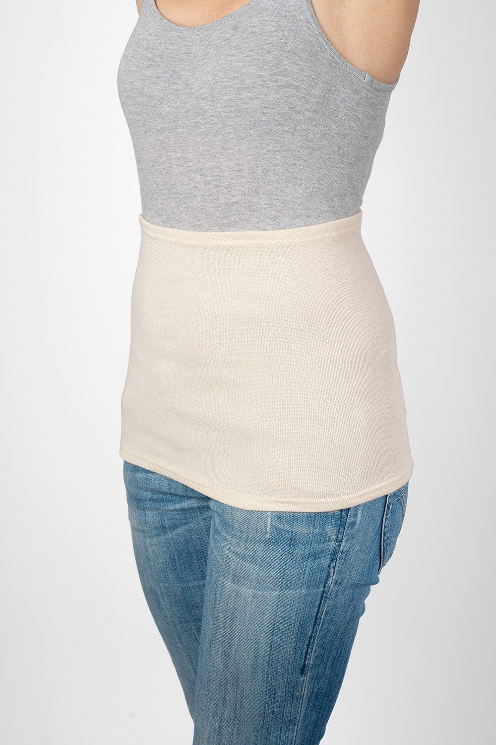 Model trägt Jeans, graues Top und leichten naturweißen Nierenwärmer aus bio Wolle (kbT), Seide, Baumwolle und Elasthan