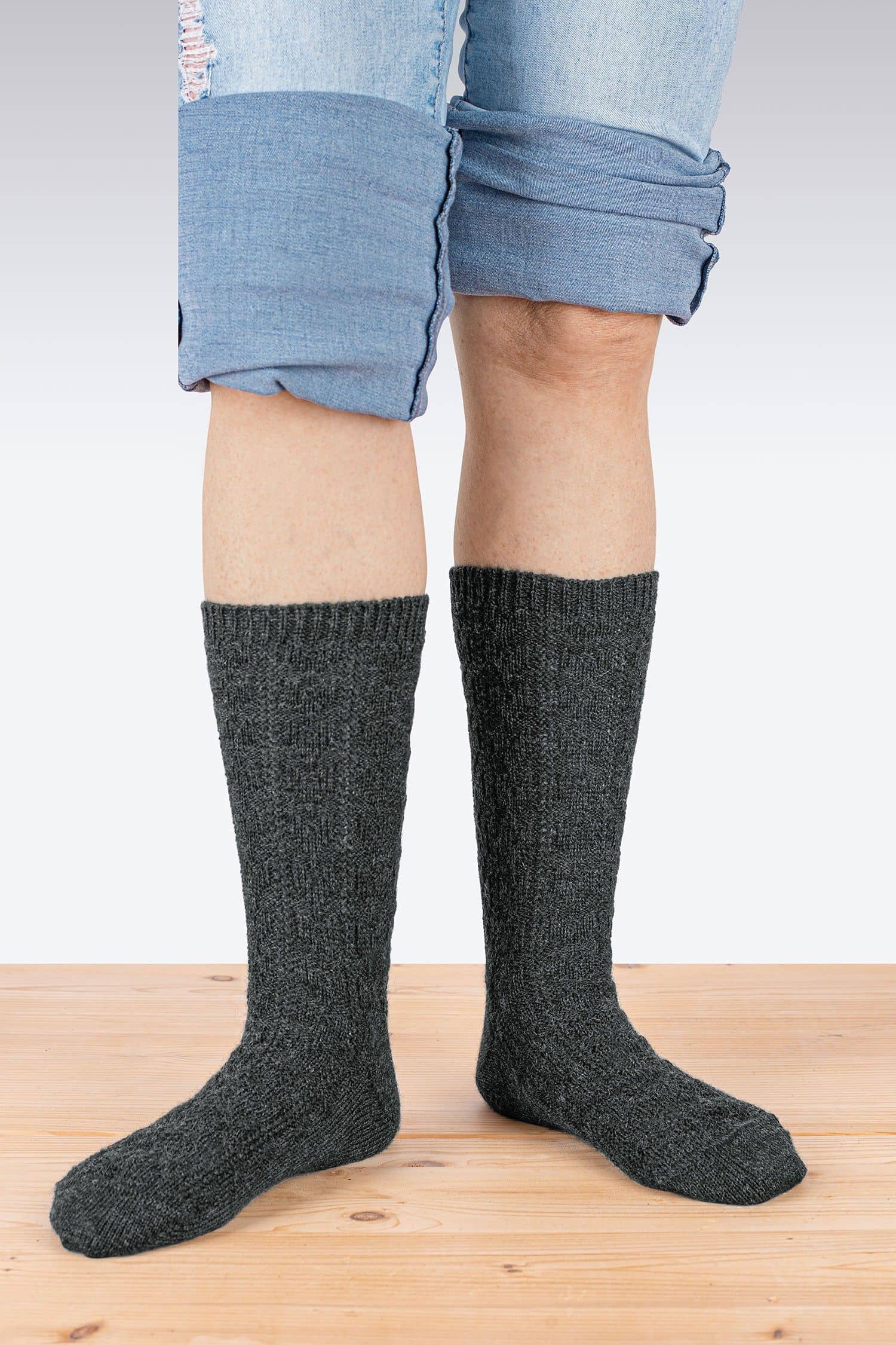 Person steht auf Holzboden und trägt anthrazitgraue Struktursocken aus bio Wolle (kbT) vom Finkhof