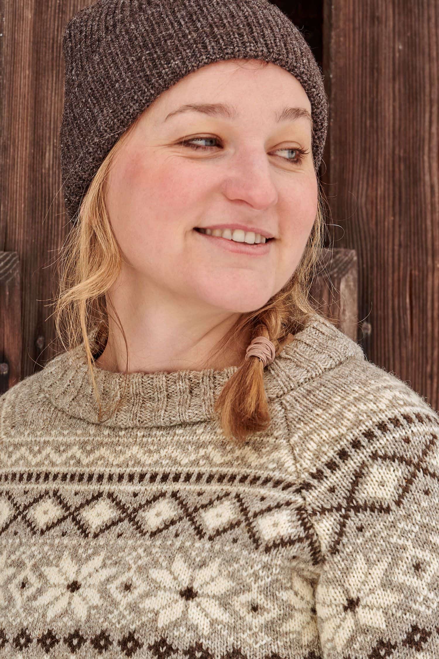 Portraitaufnahme von Frau mit hellbraunem Norwegerpulli aus bio Wolle (kbT) vom Finkhof und einer braunen Mütze