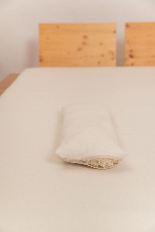 Finkhof Lendenkissen mit 20x50cm aus bio Wolle (kbT) und bio Baumwolle (kbA) auf braunem Bett mit hellem Laken, offen