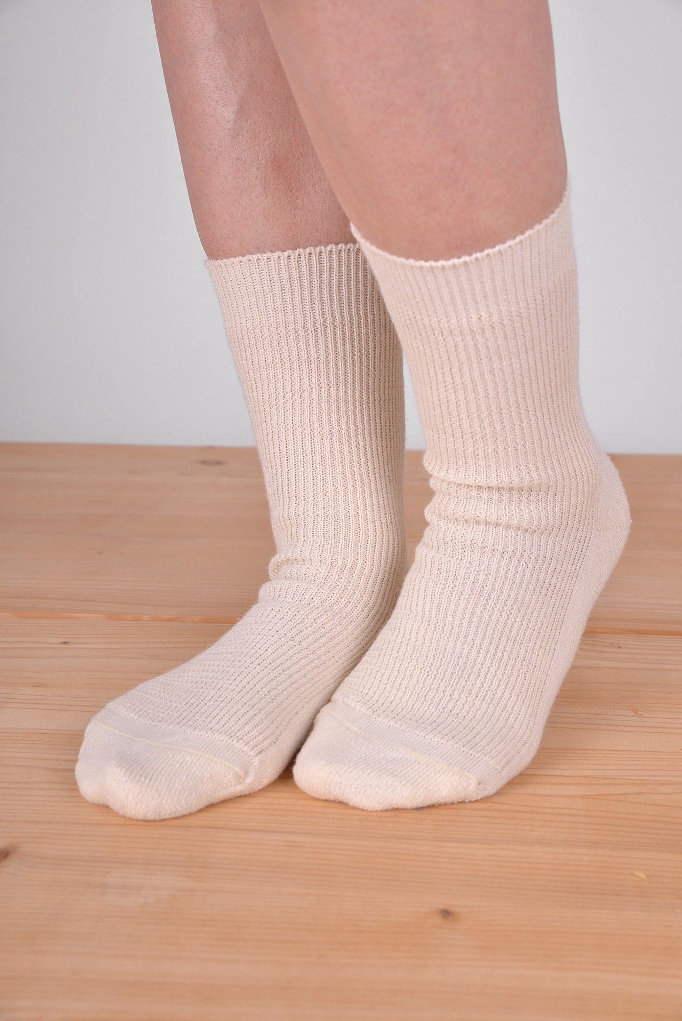 dünne Finkhof Wollsocken in naturweiß aus bio Wolle (kbT) und bio Baumwolle (kbA) getragen auf Holzboden