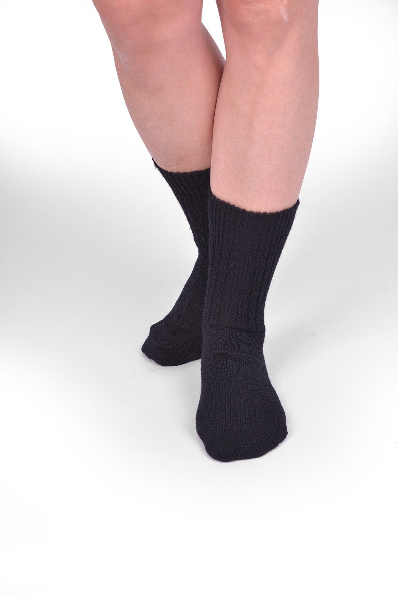 Person trägt schwarze Wollsocken aus bio Wolle (kbT) in mittlerer Dicke, von vorne