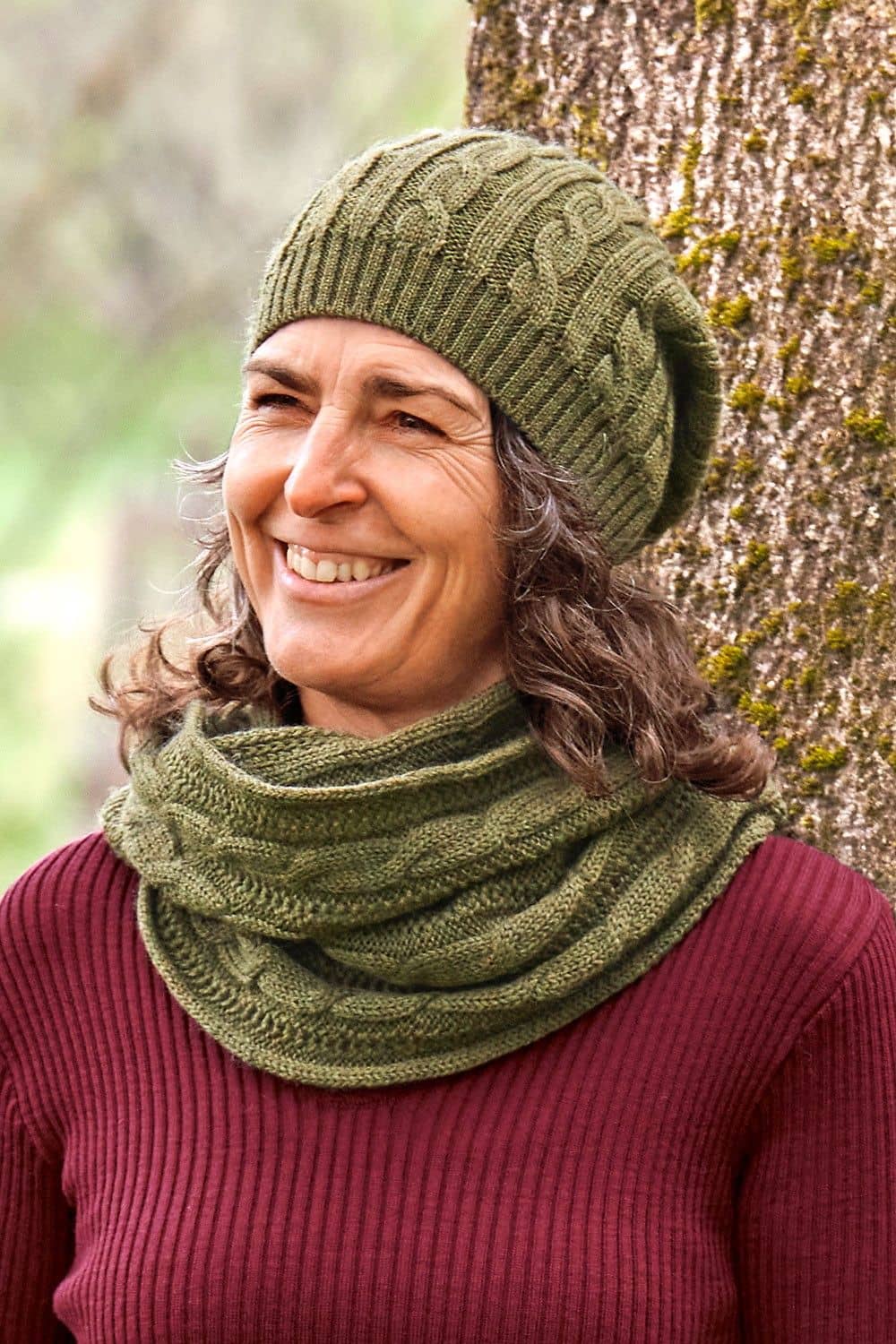 Frau mit rotem Shirt trägt eine olivegrüne Ballonmütze und einen Schal aus bio Merinwolle (kbT) vom Finkhof