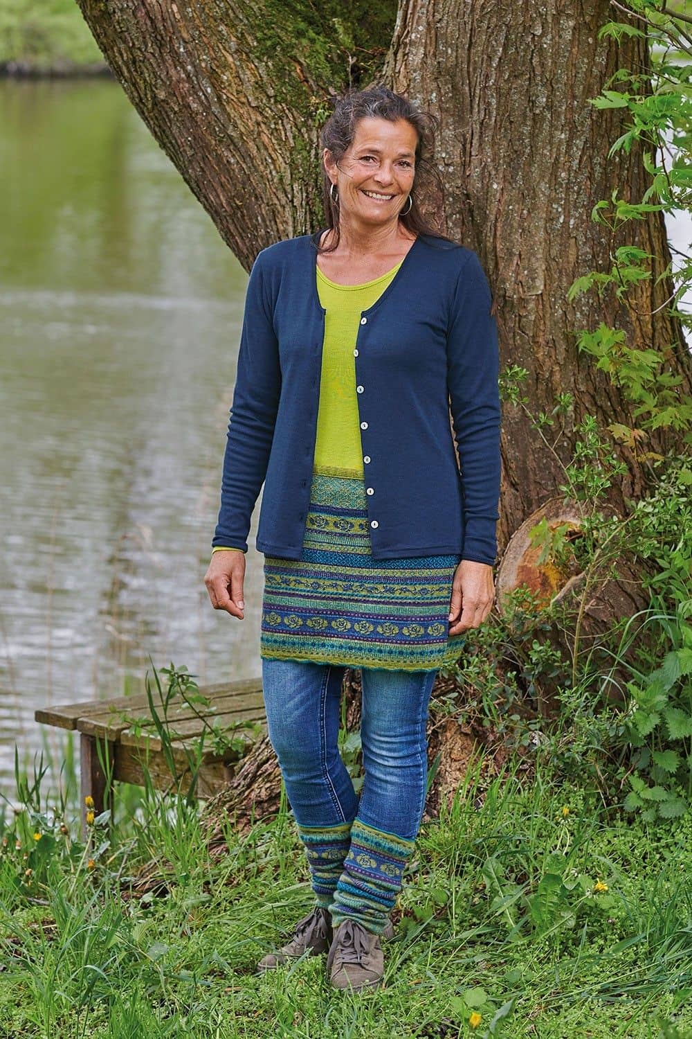 Frau trägt grünes Shirt, blauen Cardigan, gemusterten Cacheur und Beinstulpen in farn aus bio Wolle (kbT)