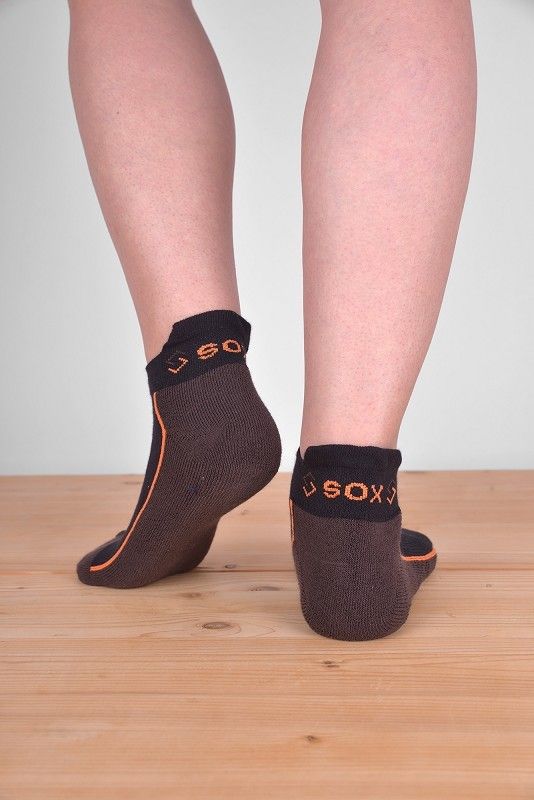 kurze braun/orange Sportsocken aus bio Baumwolle (kbA), Polyamid und Elasthan, getragen auf Holzboden von hinten