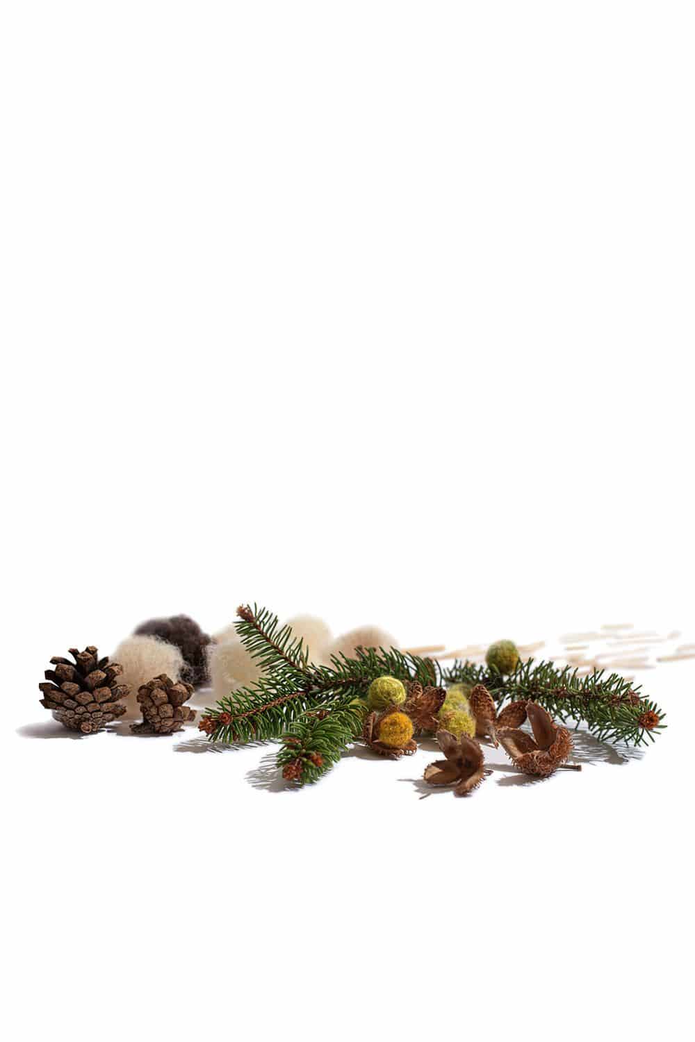 Beispielprojekt zum Buch ,,Winterfreuden" mit besticktem Kissen, Tannenzapfen und Moos
