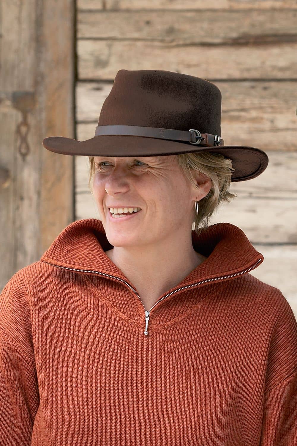 Frau mit orangem Troyer trägt dunkelbraunen Walkhut