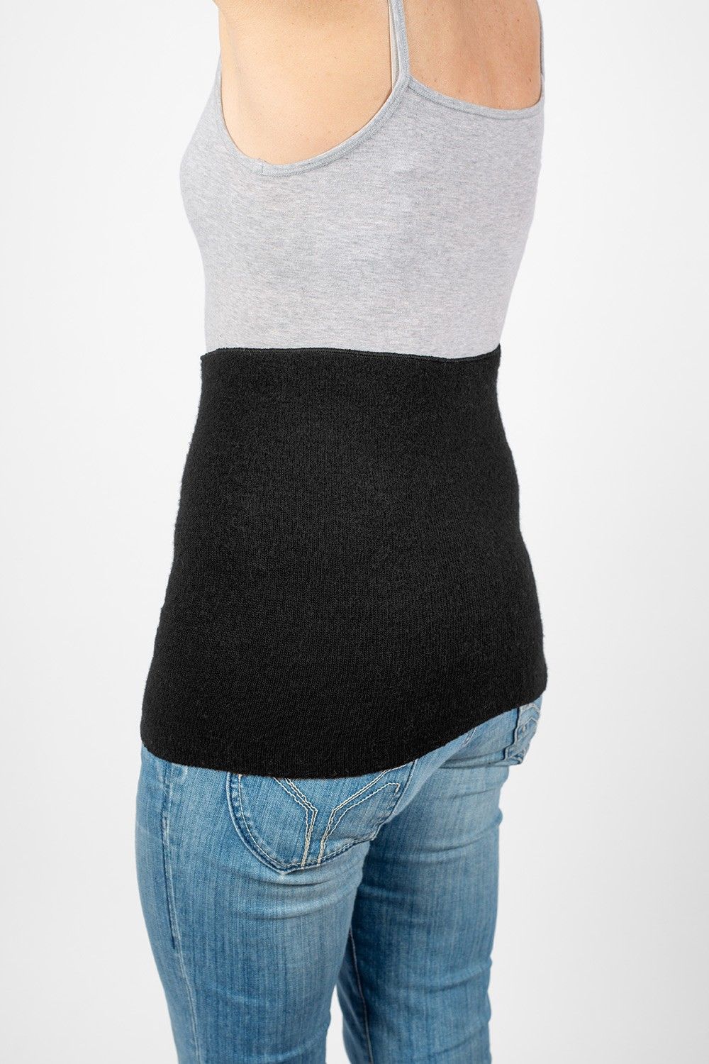 Model trägt Jeans, graues Top und warmen schwarzen Nierenwärmer aus bio Wolle (kbT), Seide, Baumwolle und Elasthan