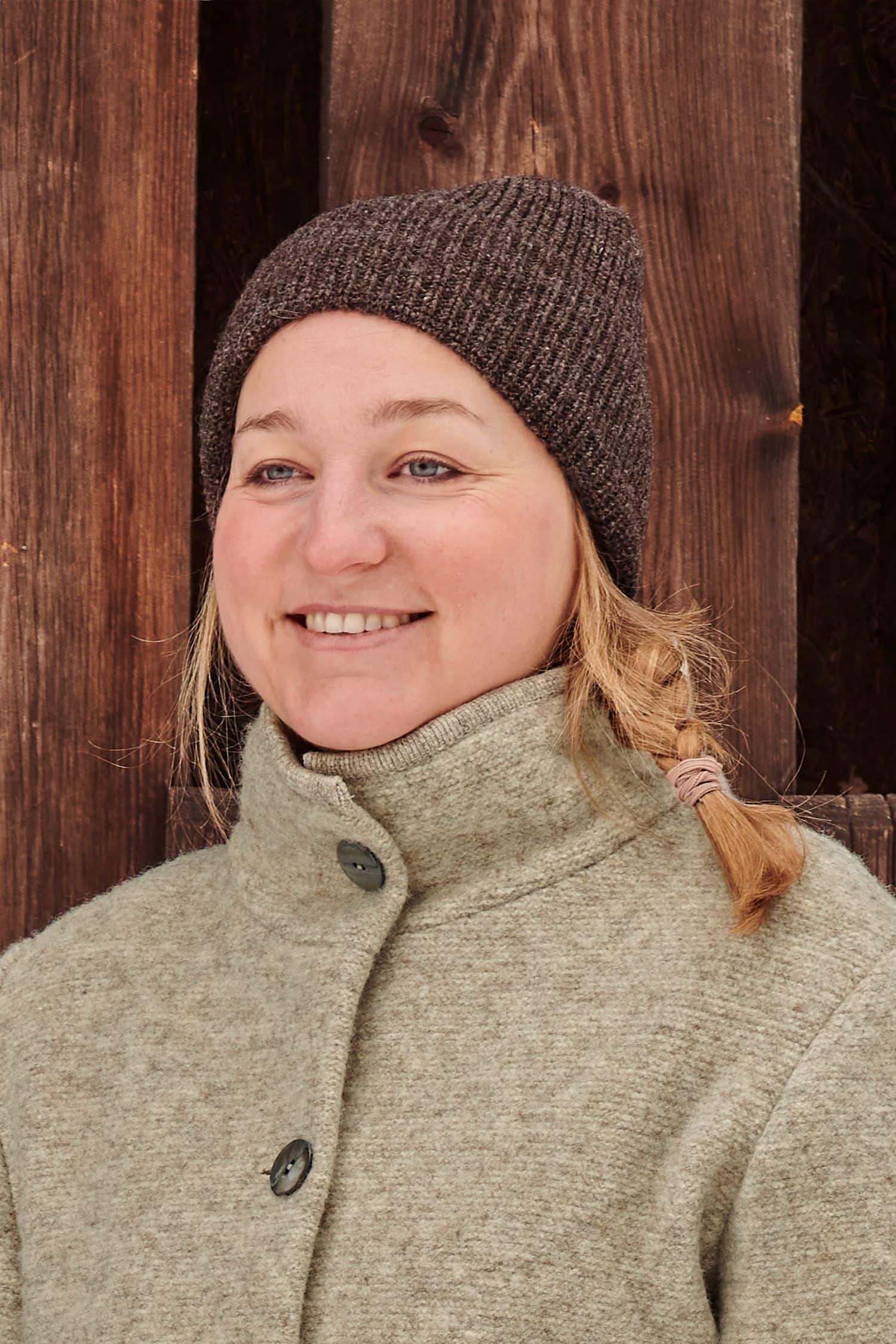 Frau trägt eine braune Finkhof Mütze aus bio Wolle (kbT) und einen Wollwalkmantel vom Finkhof