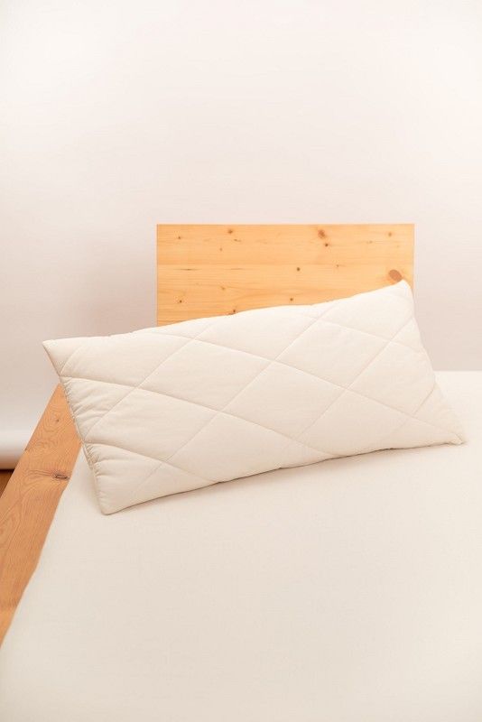 weißes Steppkissen in 40x80cm aus bio Wolle (kbT) und bio Baumwolle (kbA) vom Finkhof auf hellbraunem Bett
