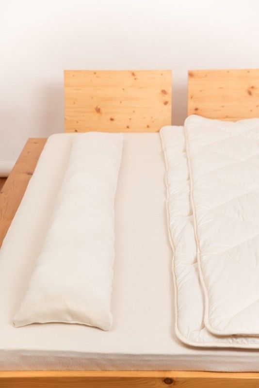 Seitenschläferkissen vom Finkhof aus bio Wolle (kbT) und bio Baumwolle (kbA) liegt auf Bett neben Bettdecke