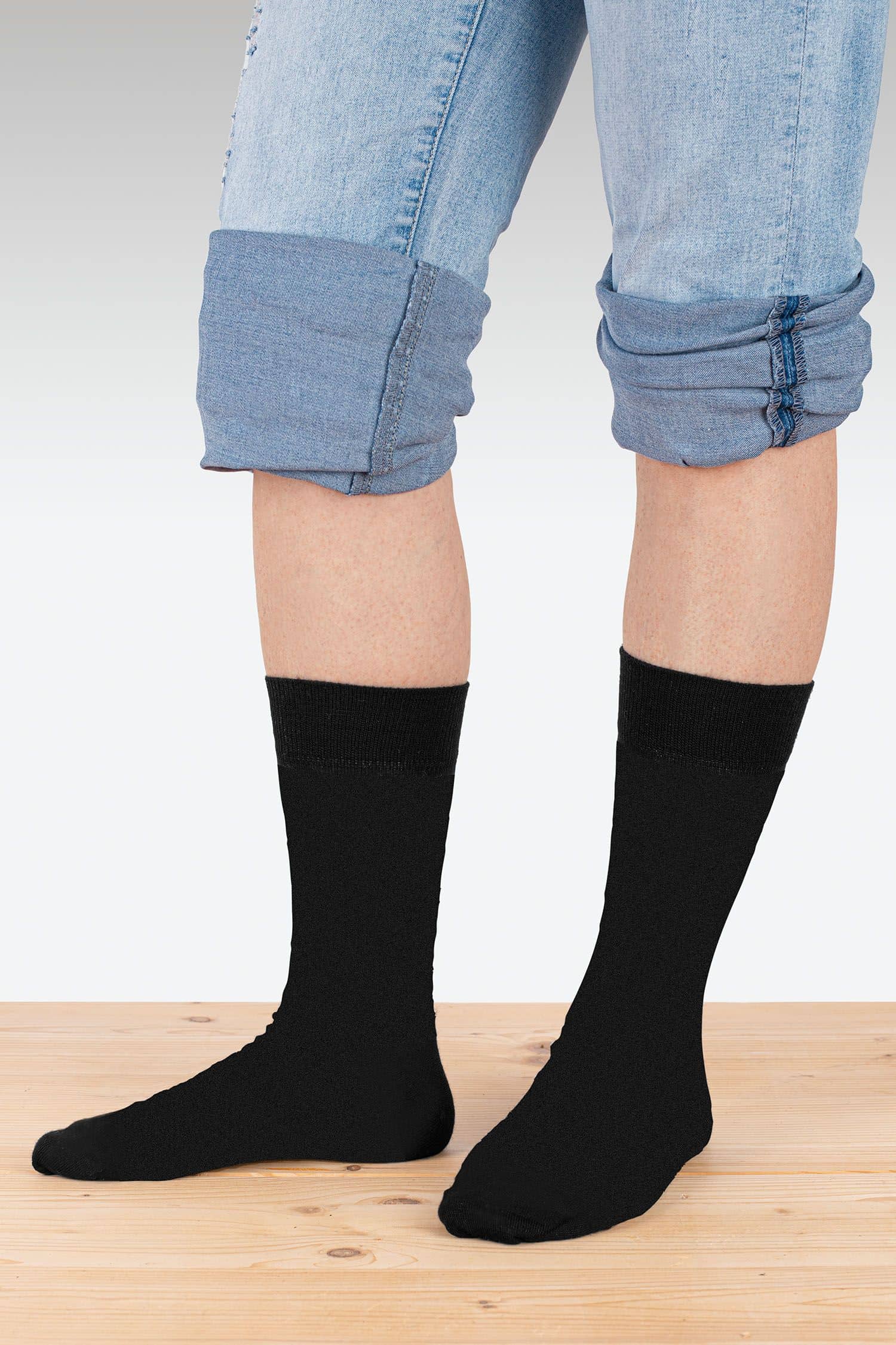 Person mit Jeans trägt schwarze feine Wollsocken vom Finkhof aus bio Wolle (kbT), bio Baumwolle (kbA) und Elasthan