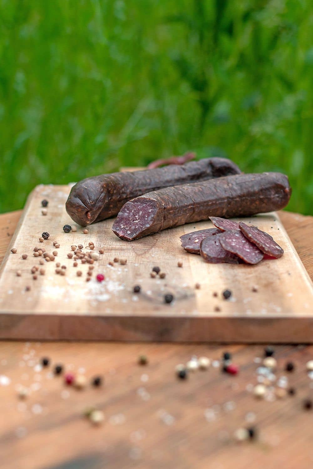 aufgeschnittene bio Schafsalami vom Finkhof auf einem Brettchen vor einer Wiese