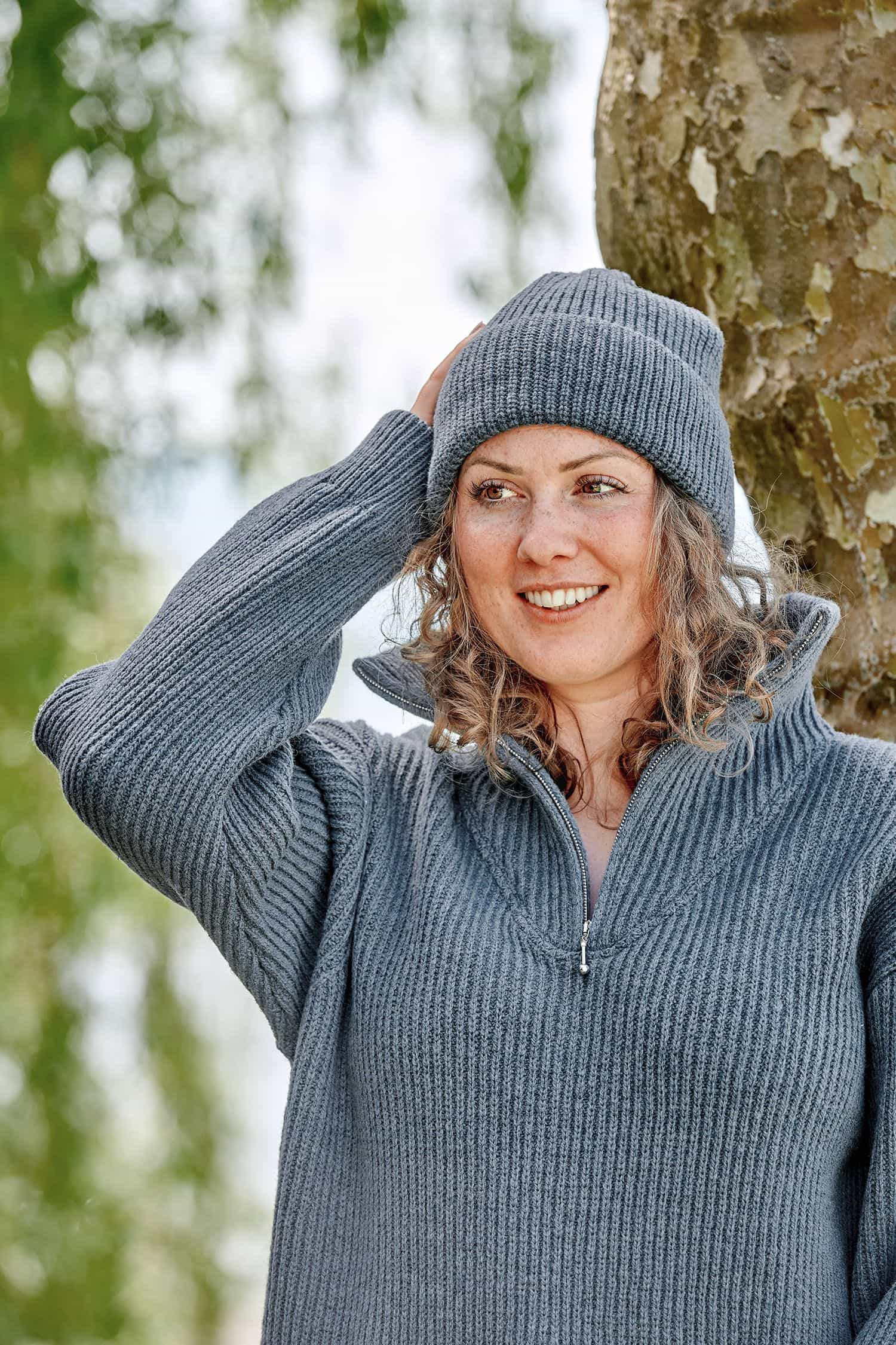 Frau trägt eine rauchblaue Finkhof Mütze aus bio Wollle (kbT) und einen Troyer