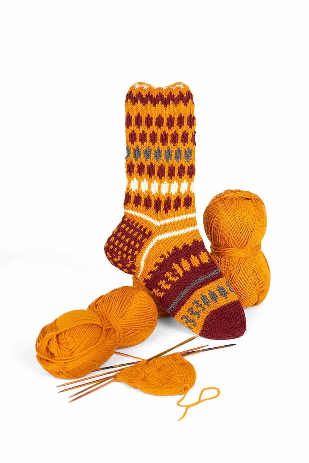feine curryfarbene Finkhof Sockenwolle in Knäulen aus bio Wolle (kbT) mit fertiger Socke, weißer Untergrund