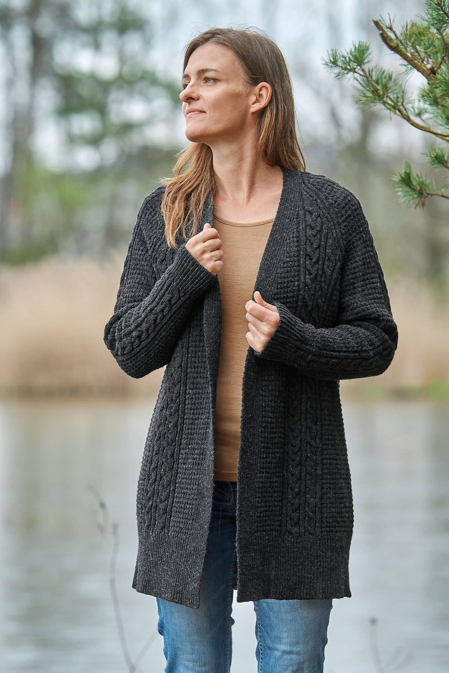 Frau trägt anthrazitfarbenen Cardigan vom Finkhof mit Zopfmuster aus bio Wolle (kbT) , unifarbiges Shirt und Jeans