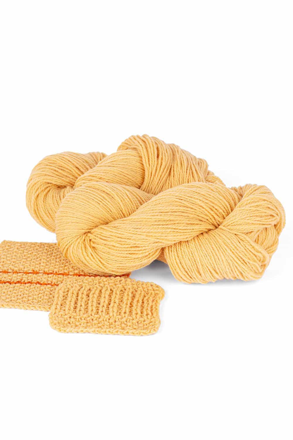 Finkhof Merinowolle dick gefärbt pastellgelb dicke pastellgelbe Finkhof Merinowolle aus bio Wolle (kbT) mit Strickstück davor, weißer Untergrund