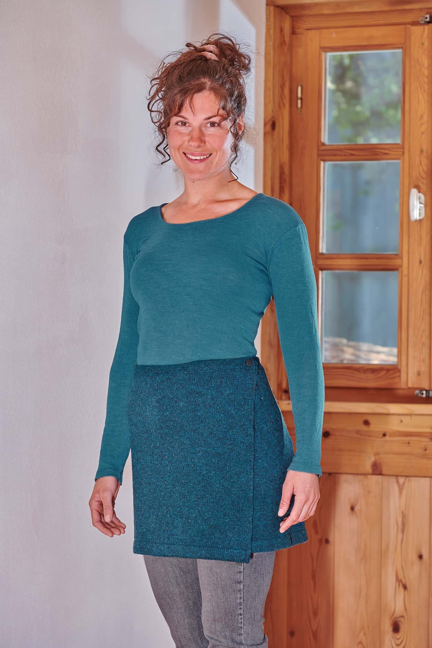 Frau trägt einen seeblauen Cacheur aus Bio-Wolle mit türkisem Shirt und einer grauen Jeans