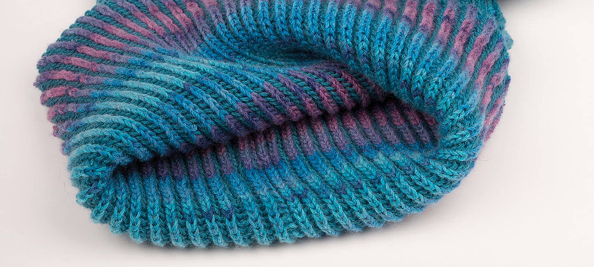 Strickanleitung Loop aus Sockenwolle blau lila gestrickter Loopschal auf weißem Untergrund