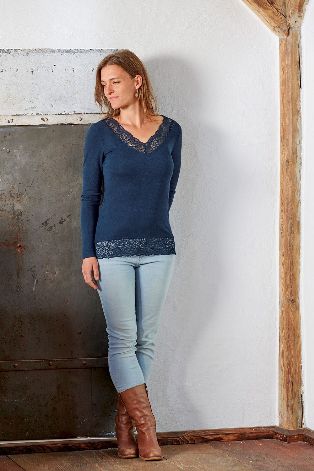 Spitzenshirt Frau trägt marineblaues Spitzenshirt aus bio Wolle (kbT) und Seide mit blauer Jeans und Stiefel