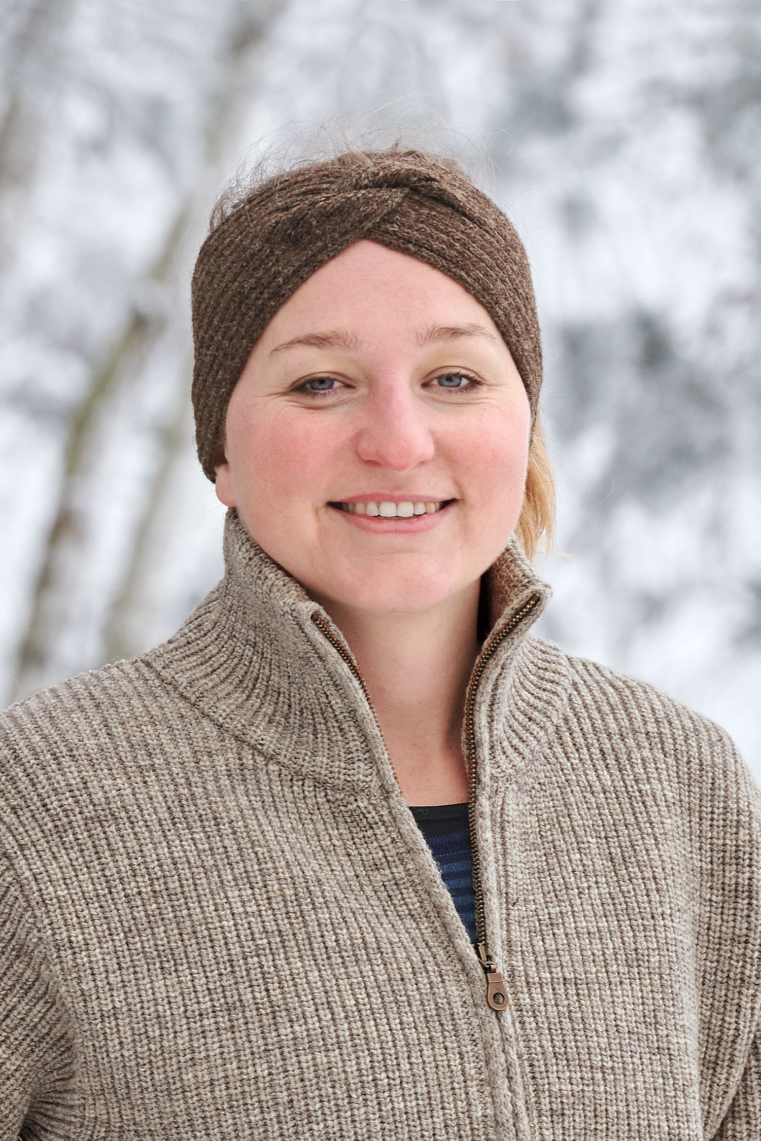 Frau trägt braunes Finkhof Stirnband mit Twist aus bio Wolle (kbT) und Finkhof Troyer