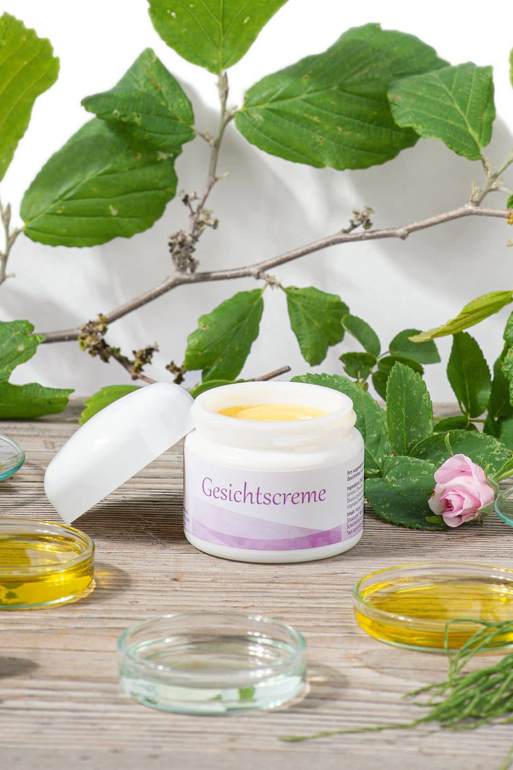 Gesichtscreme 50 ml Finkhof Gesichtscreme in Tiegel auf Stimmungsbild mit Ölen, Rosen und Ästen