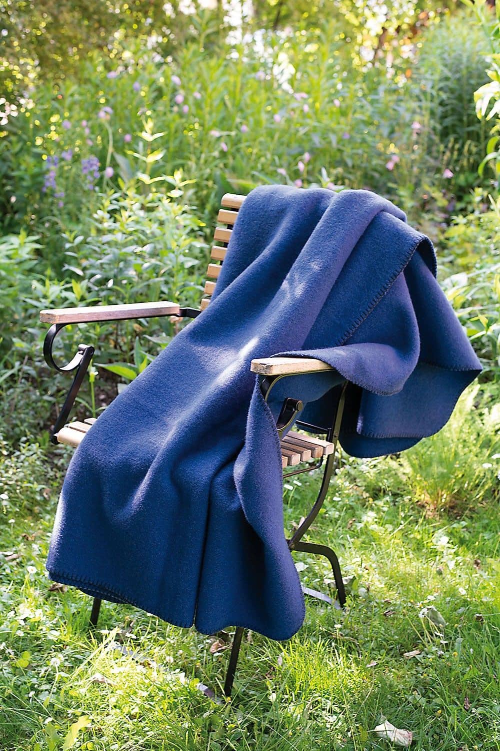 blaue Wolldecke aus bio Wolle (kbT) vom Finkhof hängt über einem Gartenstuhl