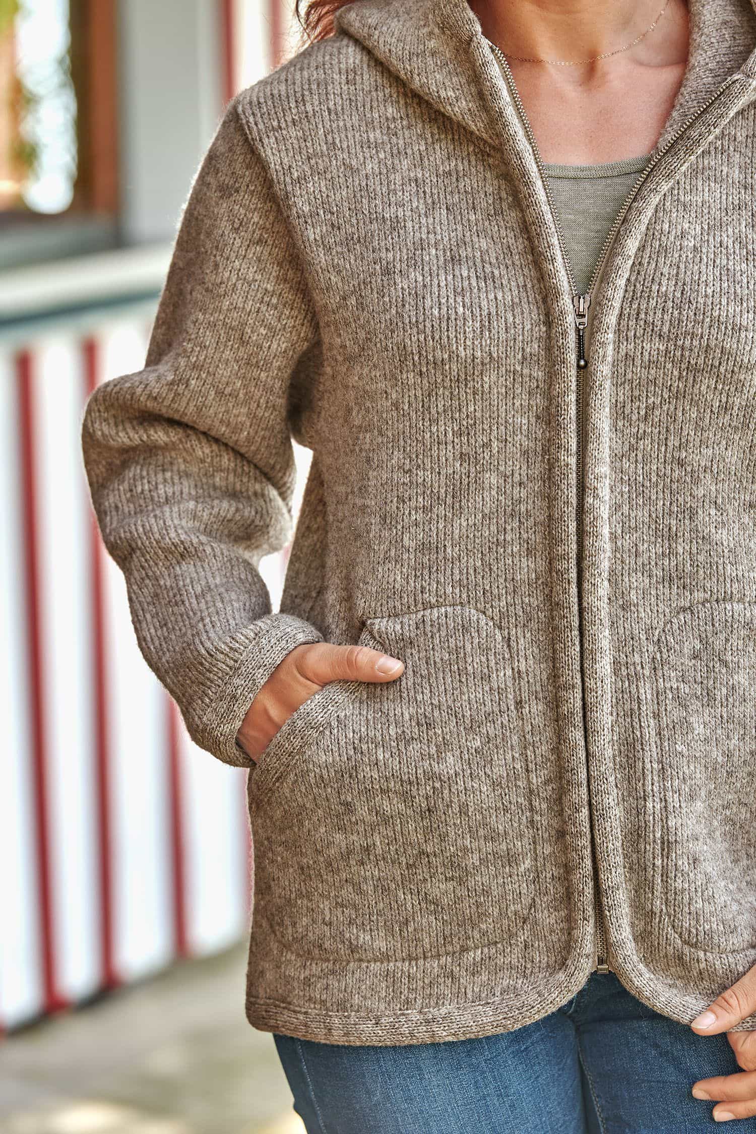 graue Kapuzenjacke vom Finkhof aus bio Wolle (kbT) wird mit Hände in den Taschen getragen