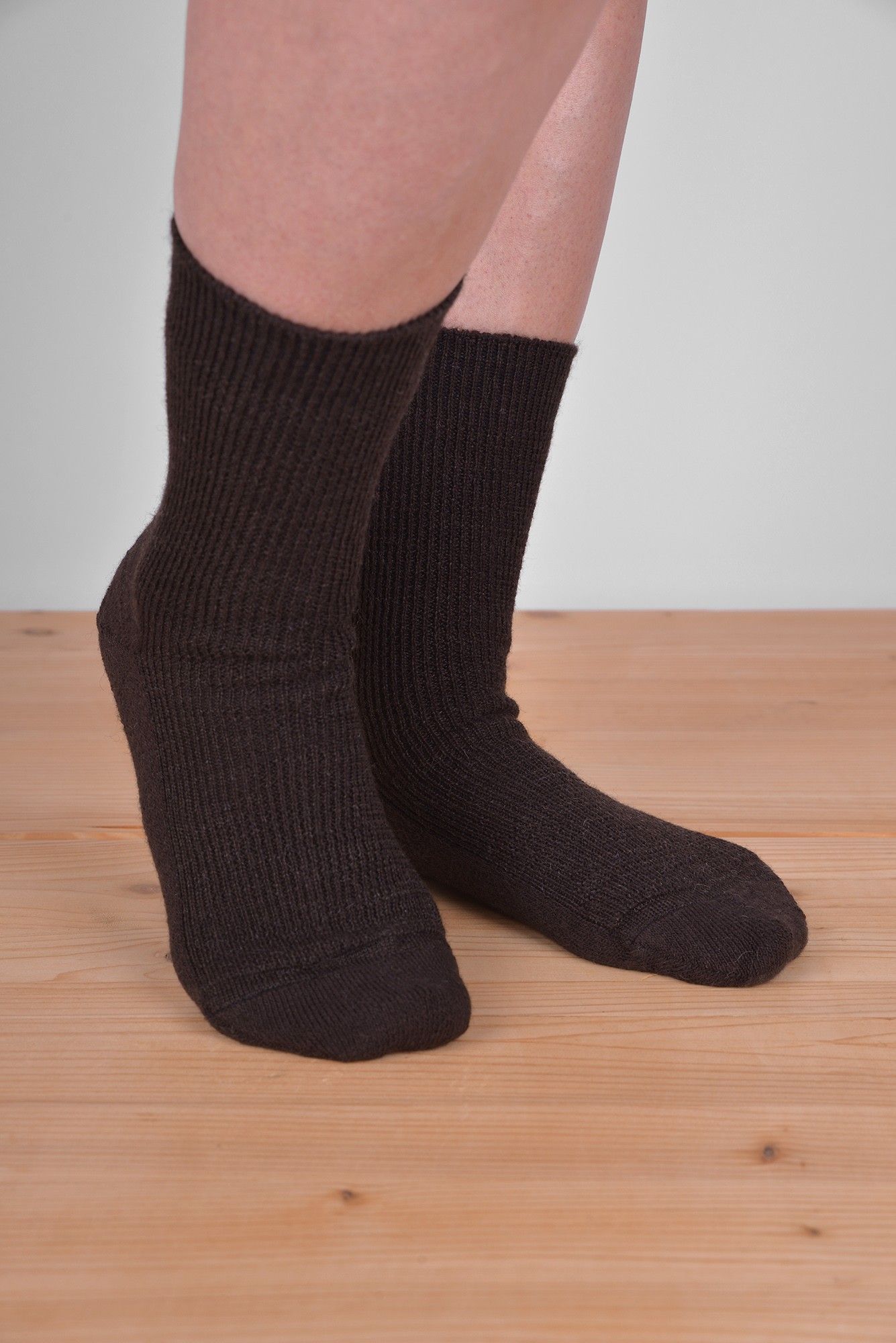 Dünne Wollsocken aus Bio-Schurwolle mit Bio-Baumwolle braune dünne Wollsocken aus bio Wolle (kbT) und bio Baumwolle (kbA) vom Finkhof an Model auf Holzboden