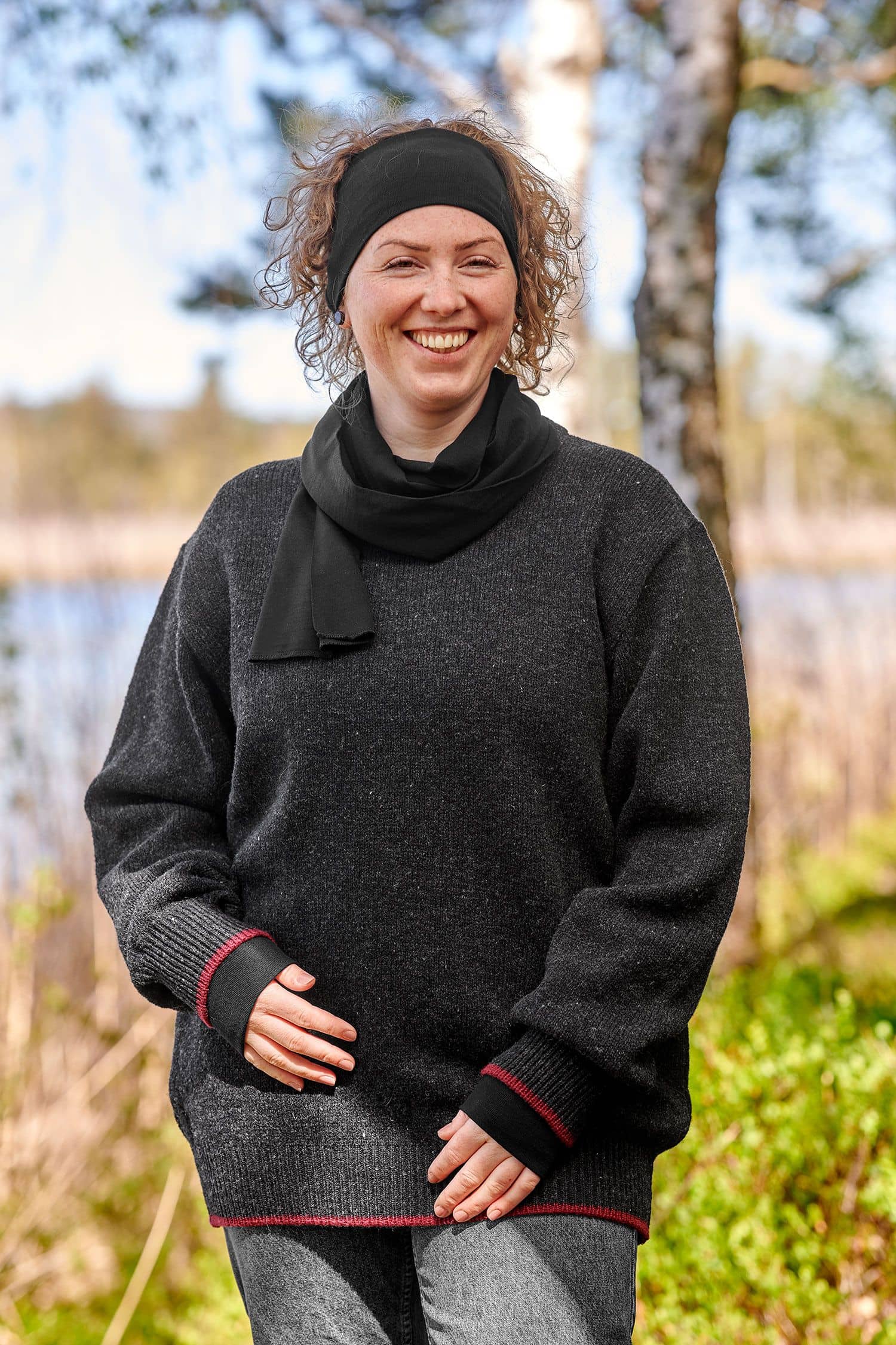 Frau trägt schwarzer Wolle Seide Schal aus bio Wolle (kbT) mit passendem Stirnband und grauem Strickpulli im Wald