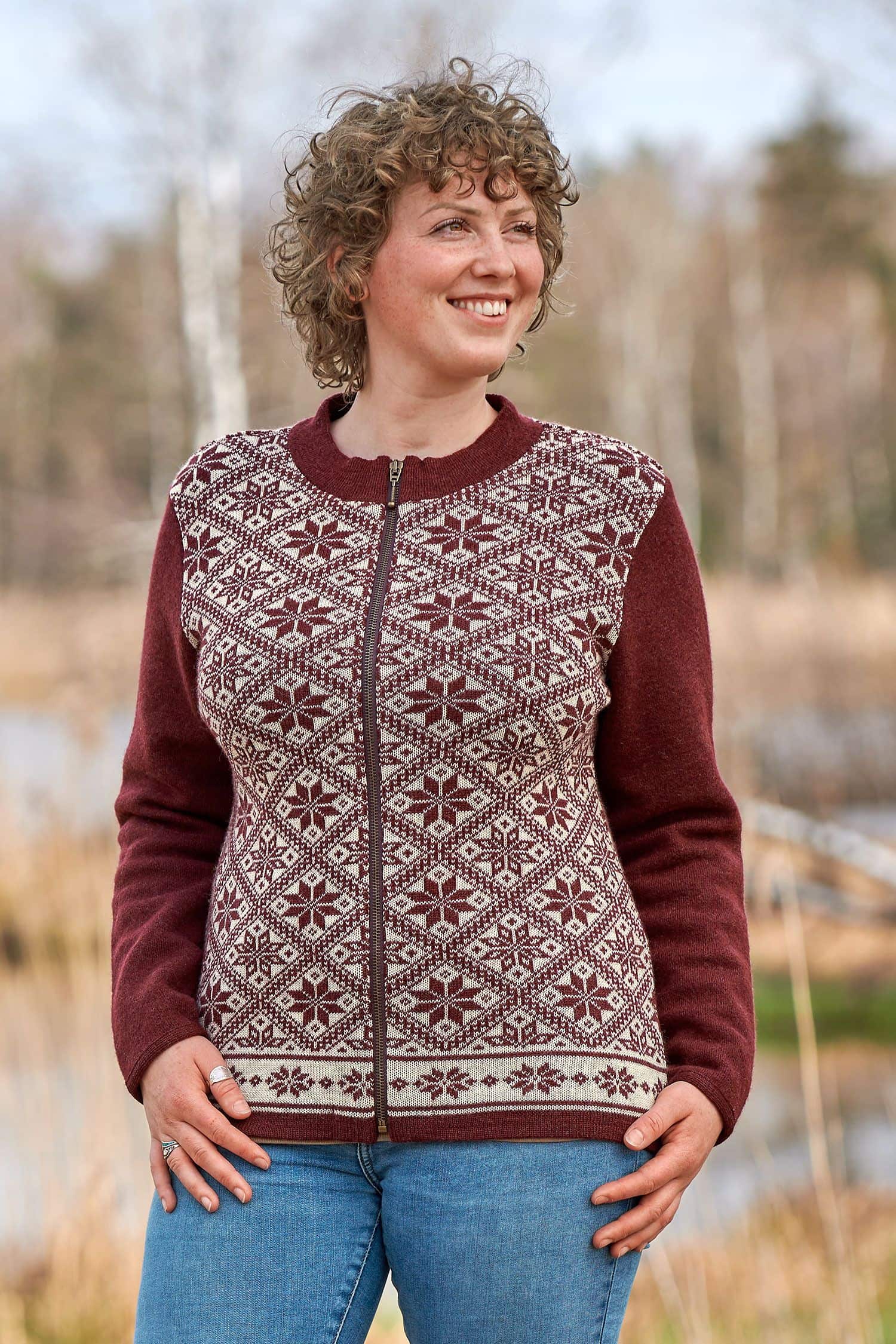 Frau trägt burgunderrote Jacke mit Norwegermuster aus bio Wolle (kbT)
