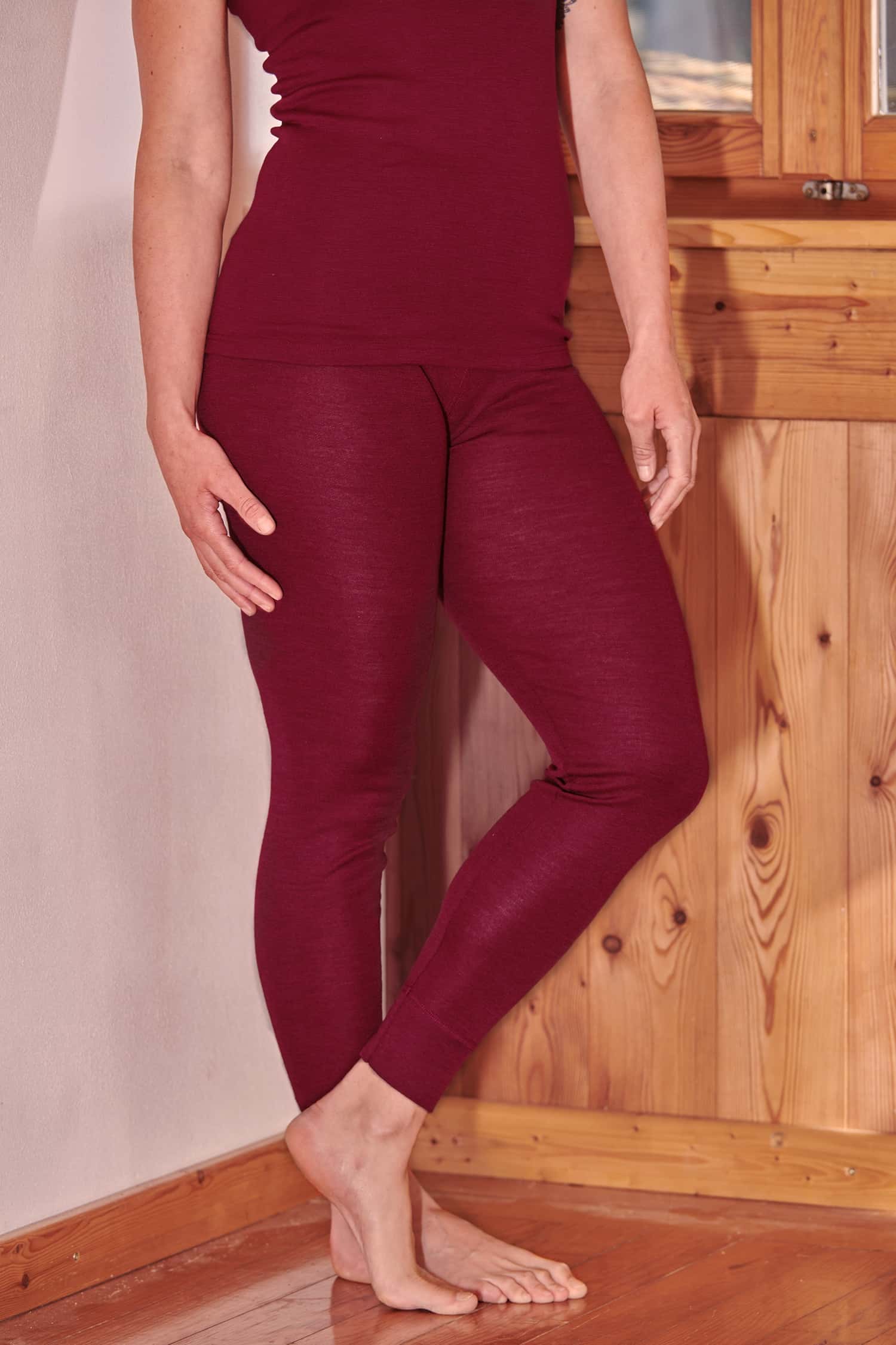 Frau trägt eine bordeauxrote lange Unterhose aus bio Wolle (kbT) und Seide und ein Langarmshirt