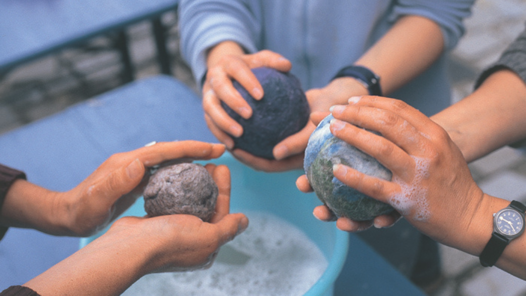 Hände von drei Personen die Bälle filzen