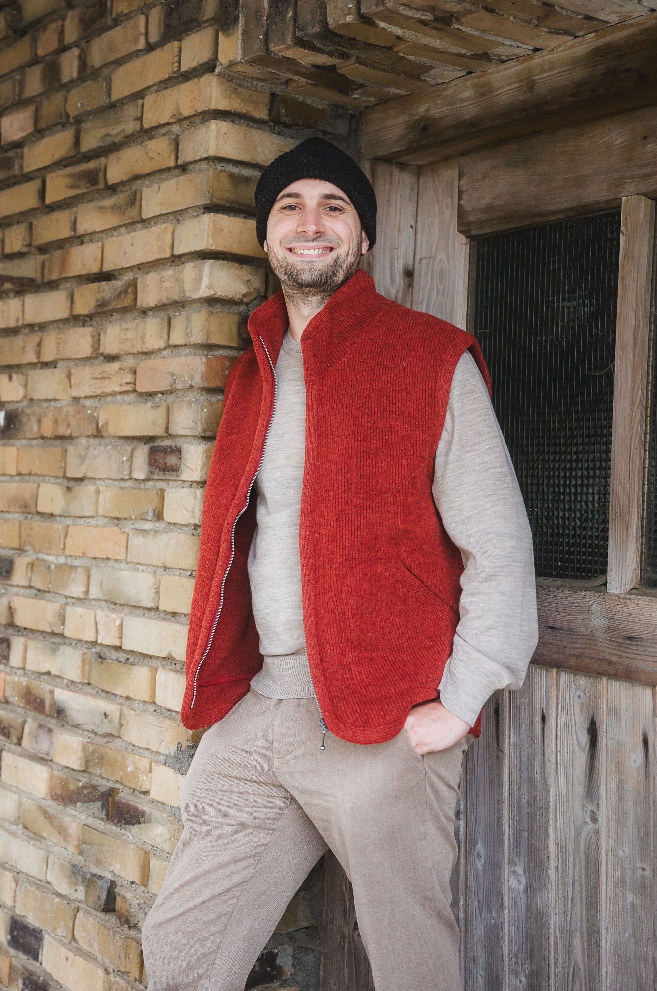Mann trägt braunes Wollshirt, eine Mütze und eine rote Wollwalkweste aus bio Wolle (kbT) vom Finkhof