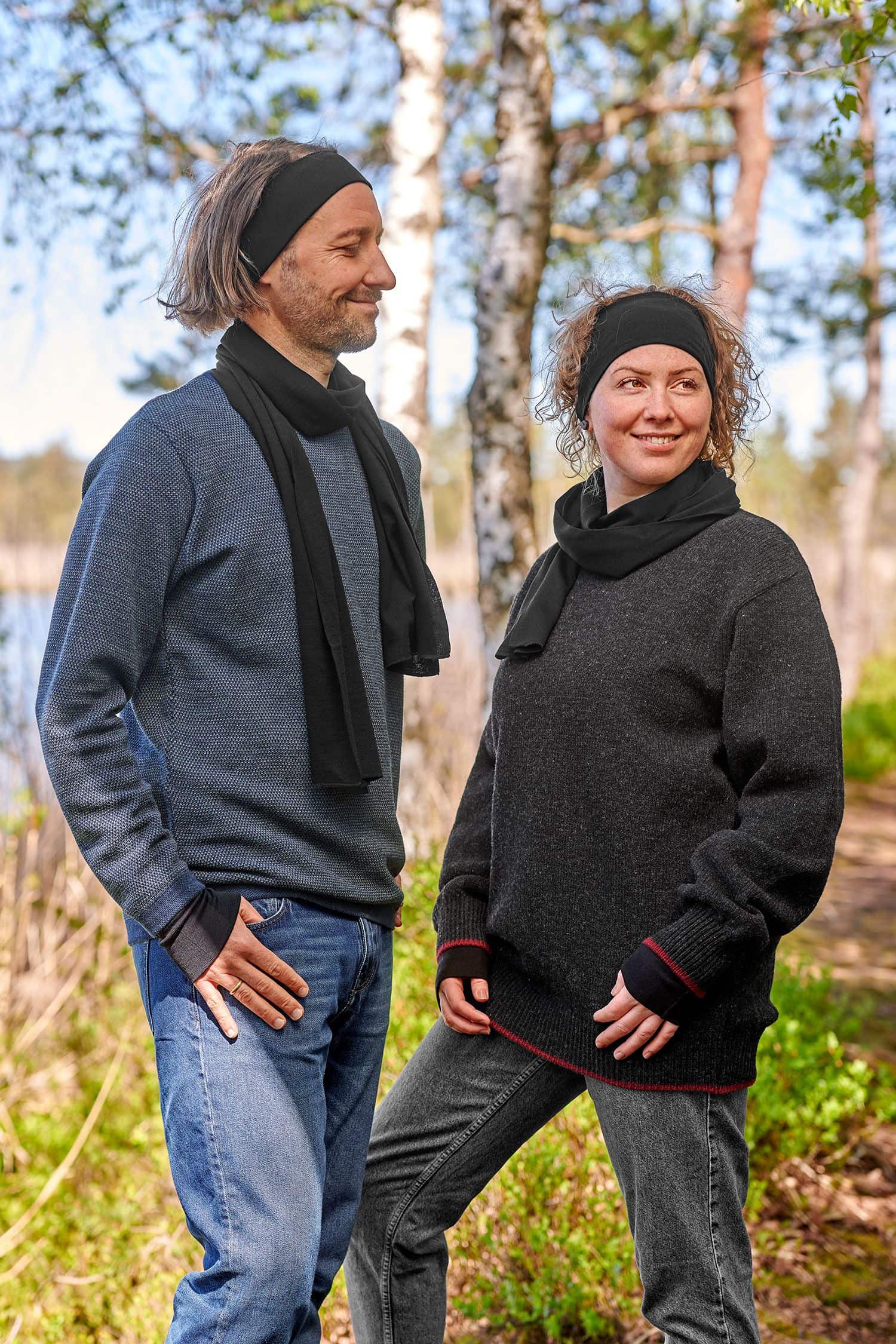 Mann und Frau mit dunklen Pullis tragen schwarze Stirnbänder, Schals und Pulswärmer aus bio Wolle (kbT) und Seide