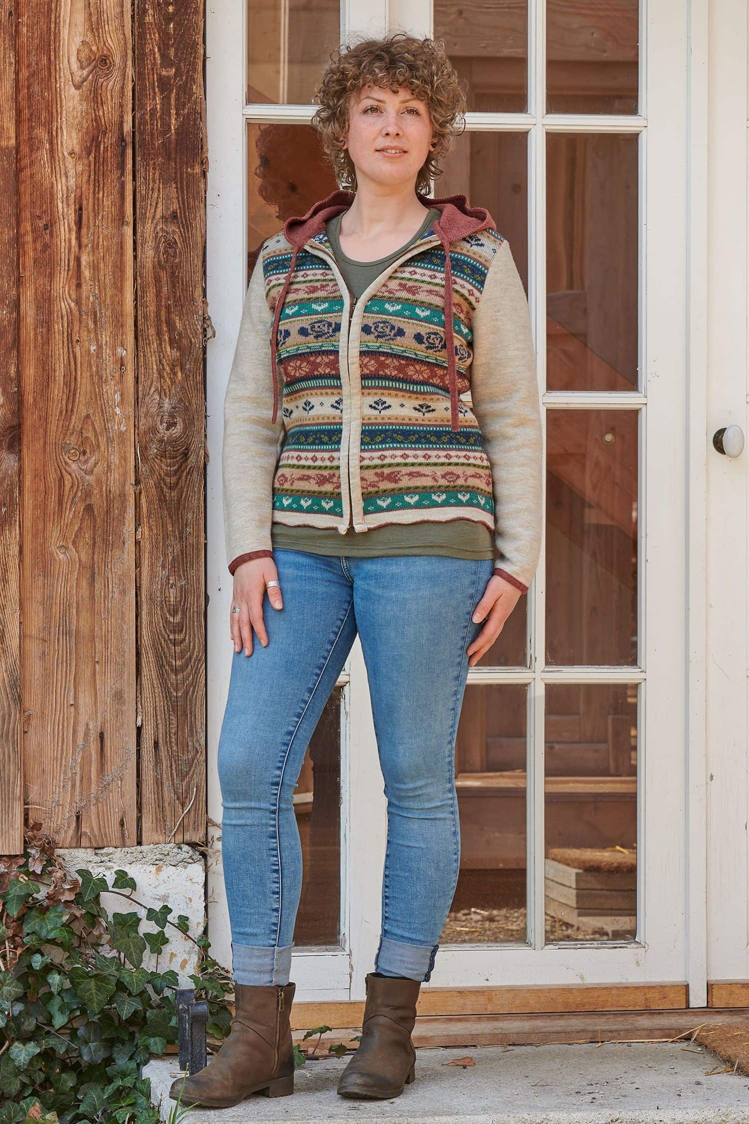 Frau steht mit Jeans vor einer Tür und trägt gemusterte Jacke Jolanda aus bio Wolle (kbT)