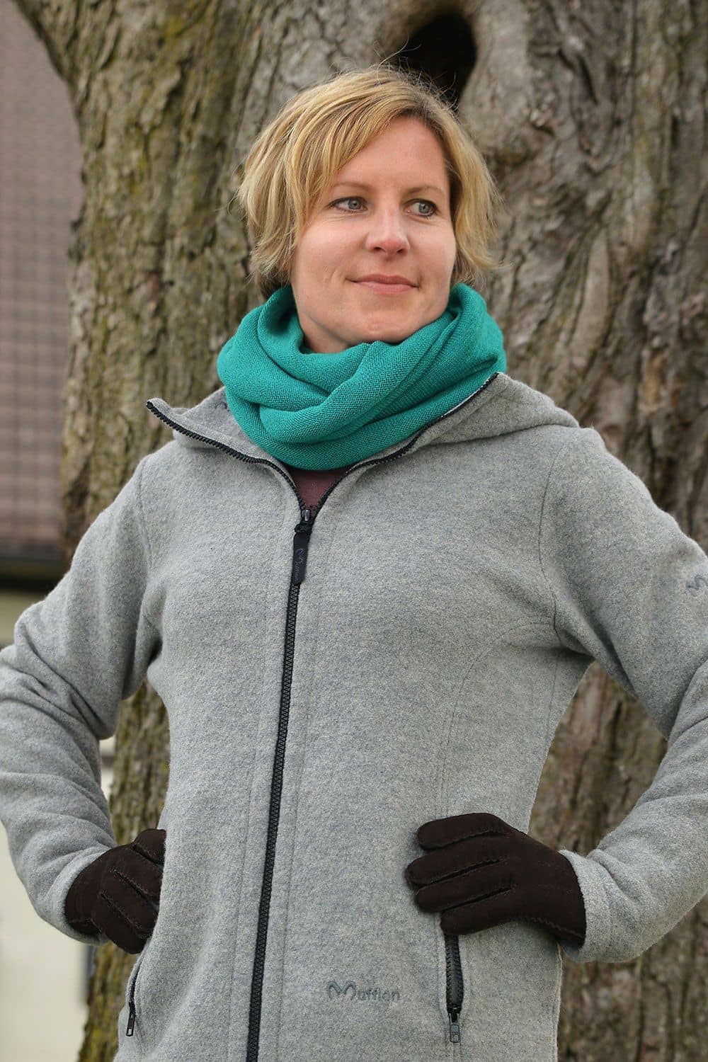 Frau mit grauer Jacke trägt türkisen Schlauchschal aus bio Wolle (kbT) vom Finkhof