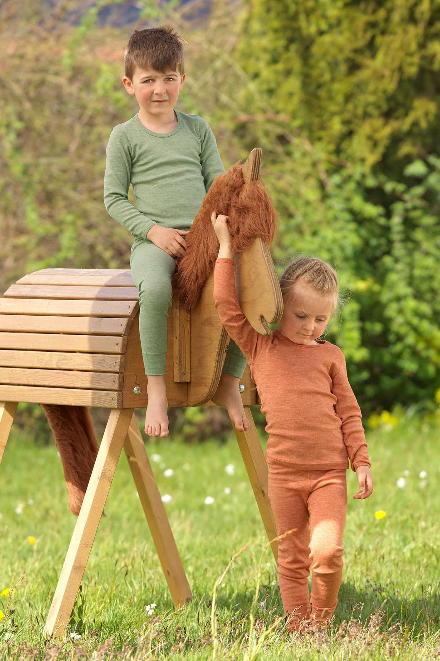 Kinder tragen Langarmshirts in orange und grün aus bio Baumwolle (kbA), bio Wolle (kbT) und Seide, dazu passende Hosen