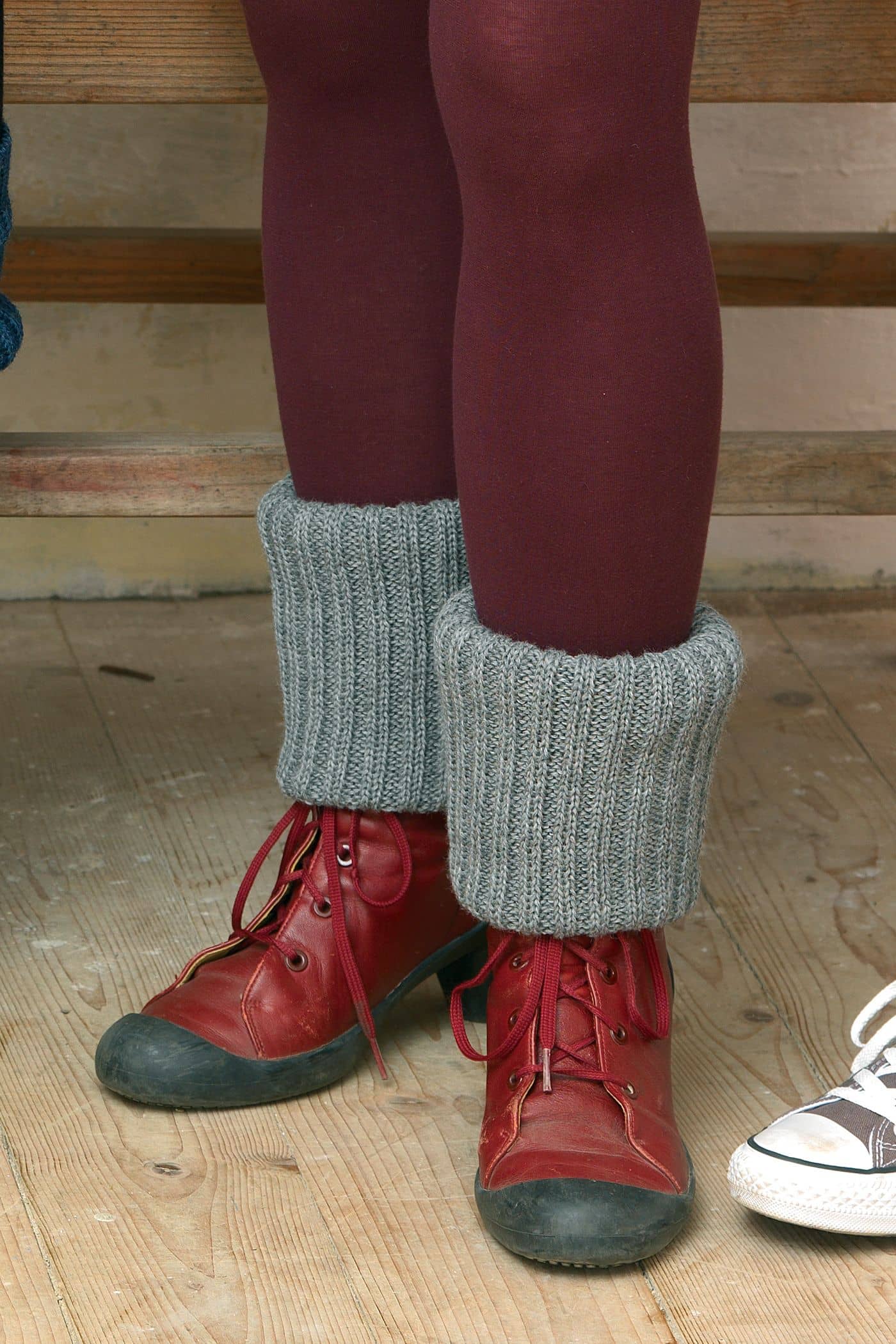 einfarbige hellgraue Beinstulpen vom Finkhof aus bio Wolle (kbT) mit roter Strumpfhose und Stiefeln