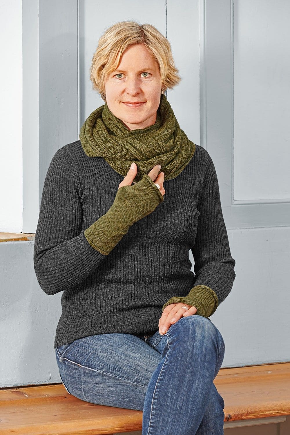 Frau mit grauem Rippshirt trägt Schal und olivegrüne Handstulpen aus bio Wolle (kbT) vom Finkhof