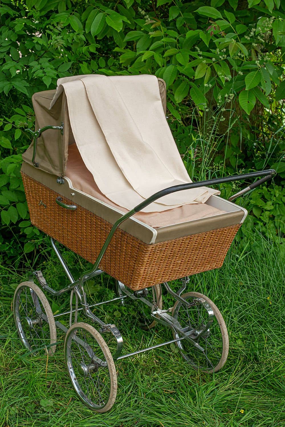helles Moltontuch aus bio Baumwolle (kbA) über alten Kinderwagen mit Korbschale gelegt