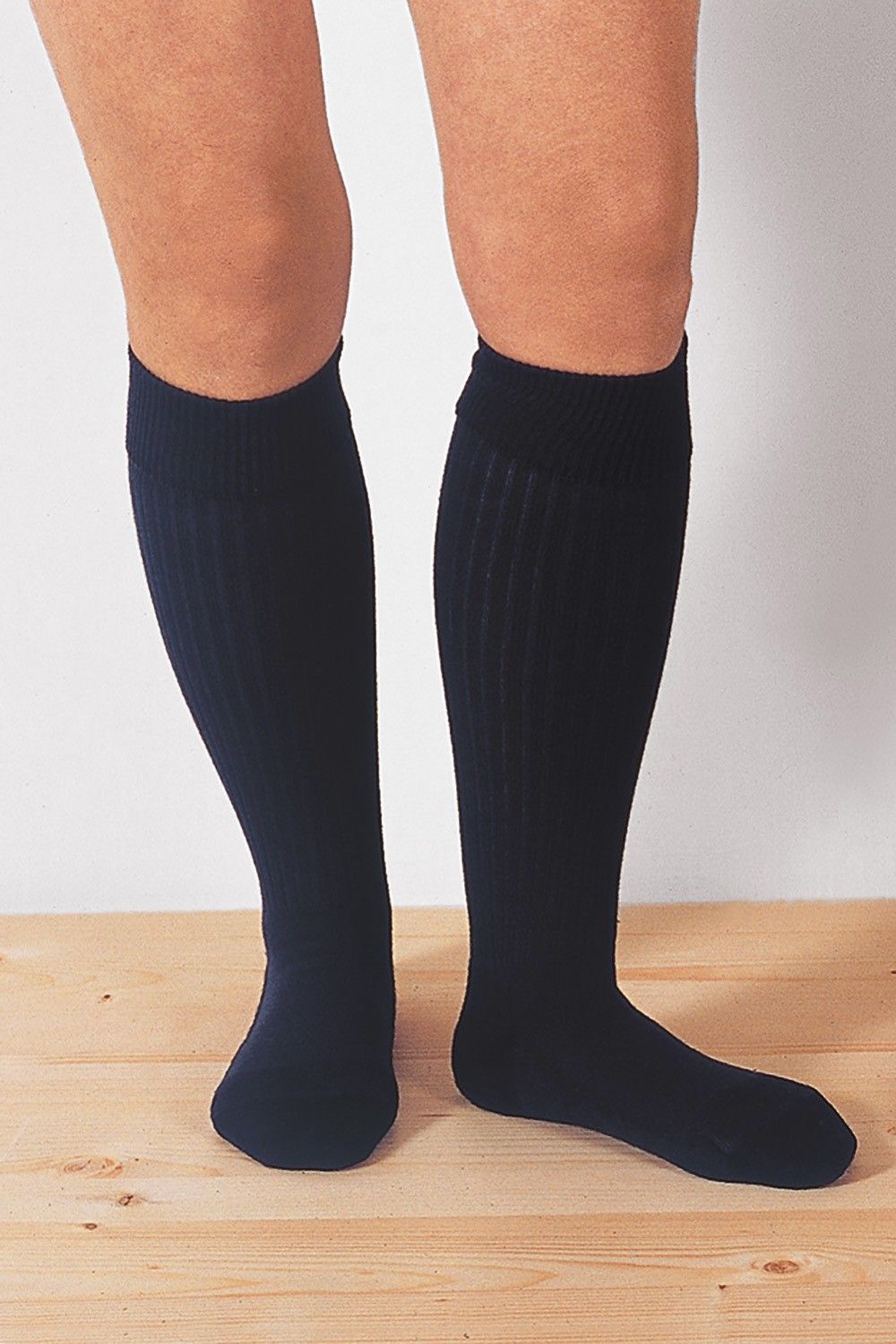 Person trägt marineblaue warme Kniestrümpfe aus bio Wolle (kbT), Baumwolle (kbA), Elasthan vom Finkhof, auf Holzboden