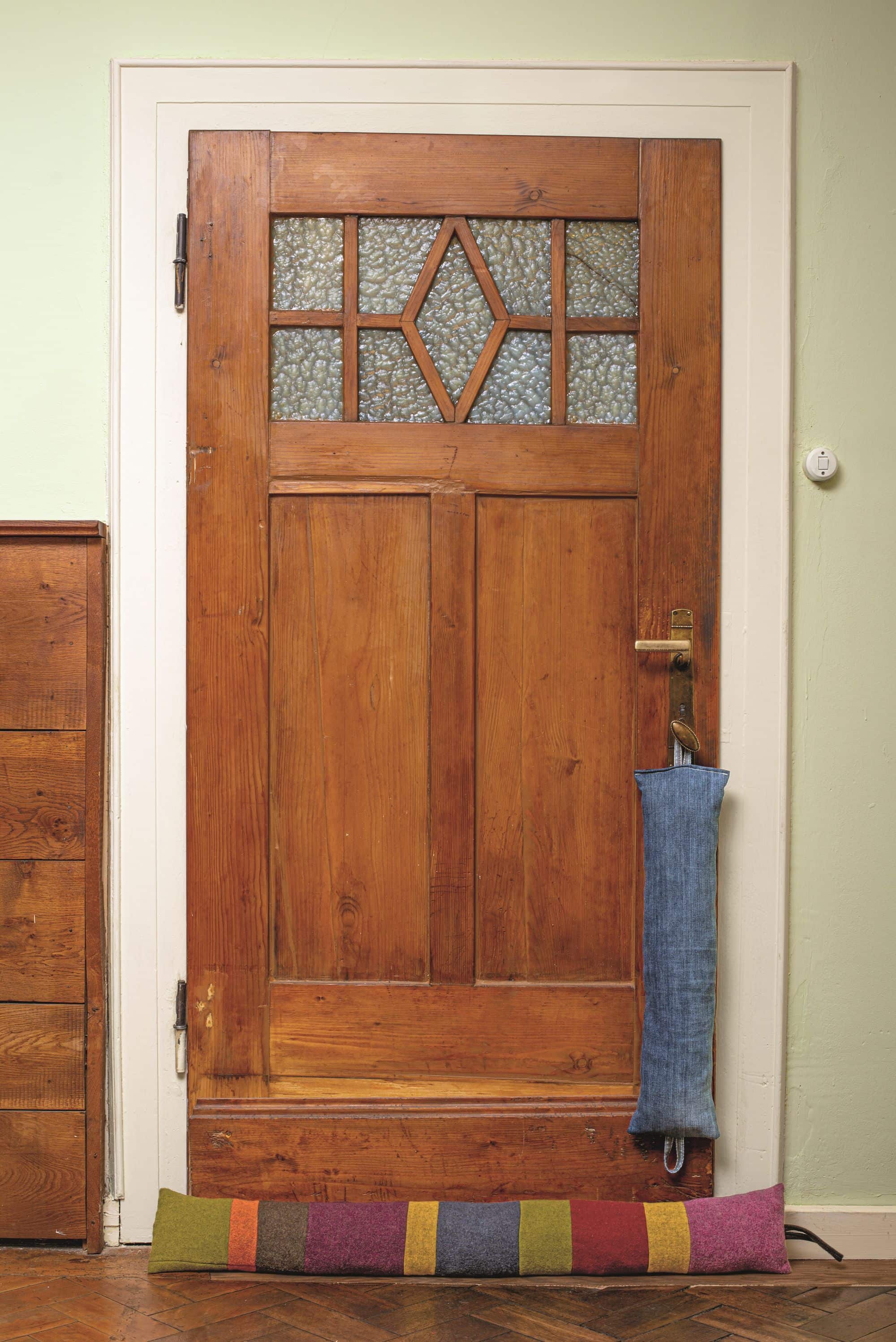 gestreifte Zugluftschlange liegt an Tür, die aus Jeans hängt an Tür sie sind Beispiele für Buch ,,Flicken und Stopfen"