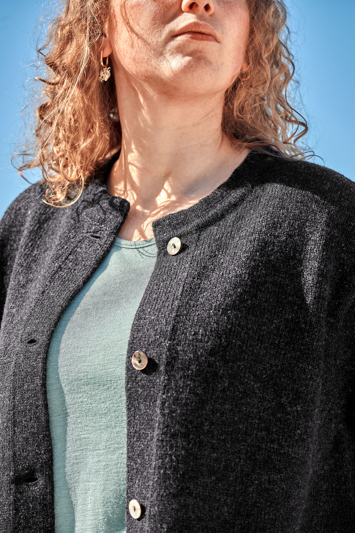 Frau trägt anthrazitgrauen Strickmantel aus bio Wolle (kbt) vom Finkhof, ein blaues Shirt