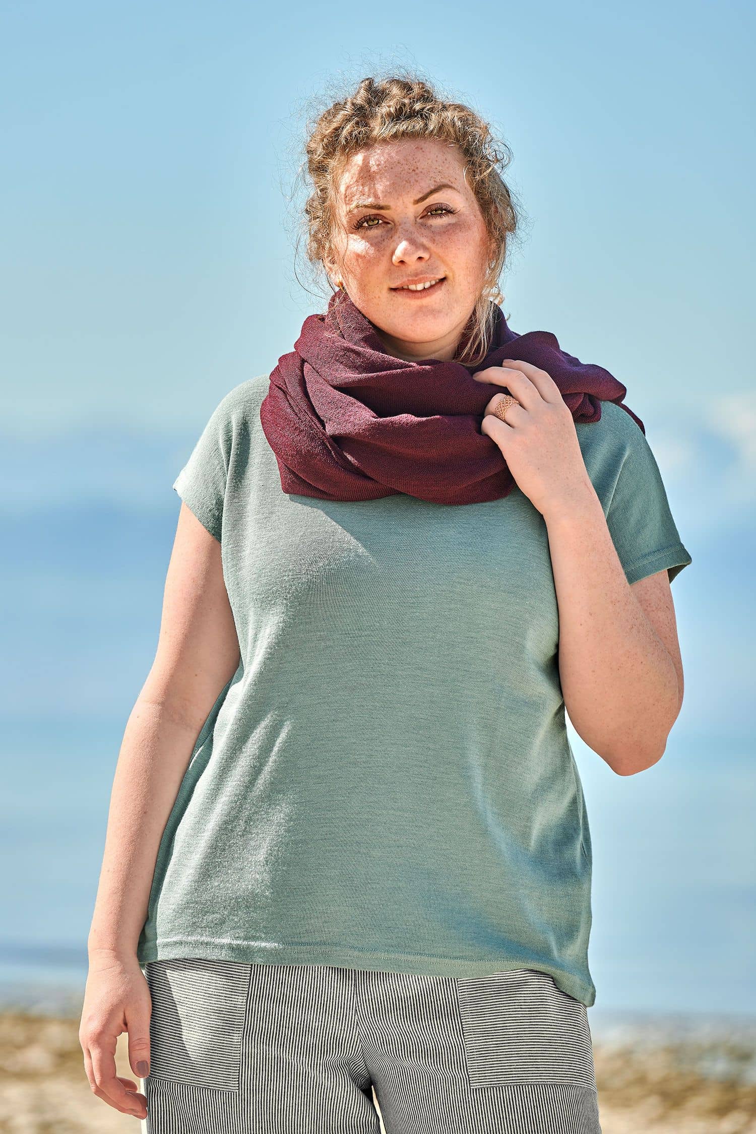 Feiner Merinoschal burgund Frau mut blauem Shirt trägt einen burgunderroten feinen Merinoschal aus bio Wolle (kbT) vom Finkhof